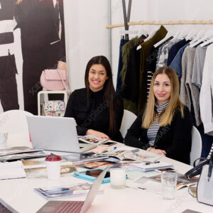 Portrait smiling fashion buyers meeting in messy office.